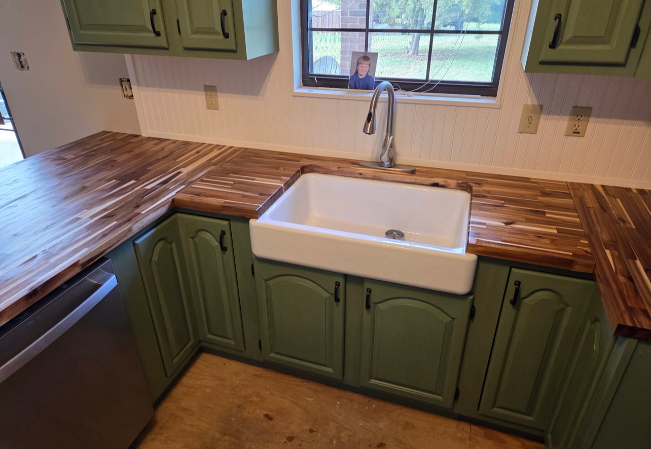Green cabinet kitchen with white farmhouse sink and wood counters